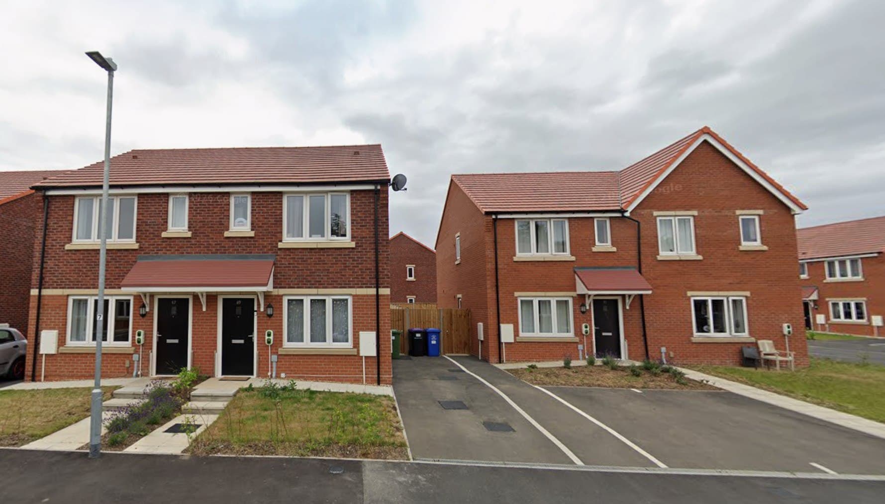 Alcorn Green, Boston: street view of completed two-storey homes in red brick with terracotta pitched roofs, canopy porches and block-paved drives along the development road, Platform Housing Group affordable scheme