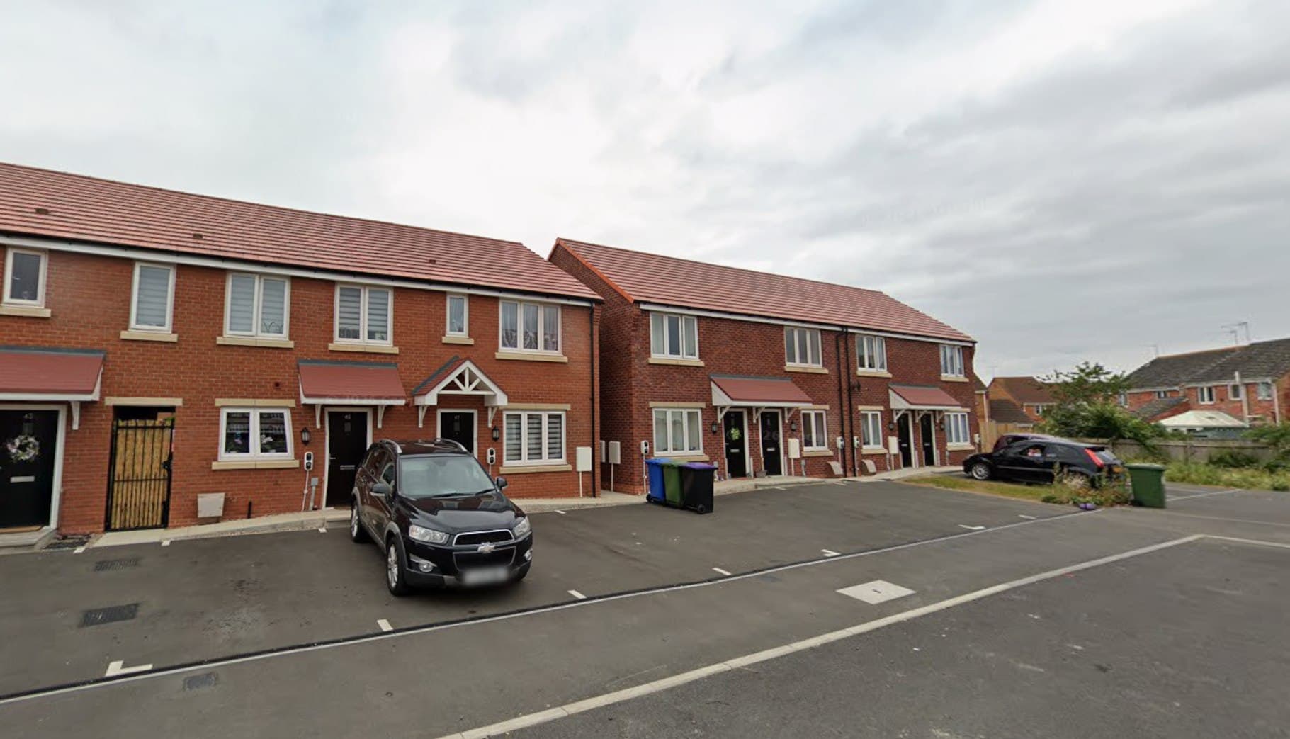 Alcorn Green, Boston: red-brick terrace and semi-detached homes ranged around a cul-de-sac with marked parking bays and a parked car, Platform Housing Group affordable scheme