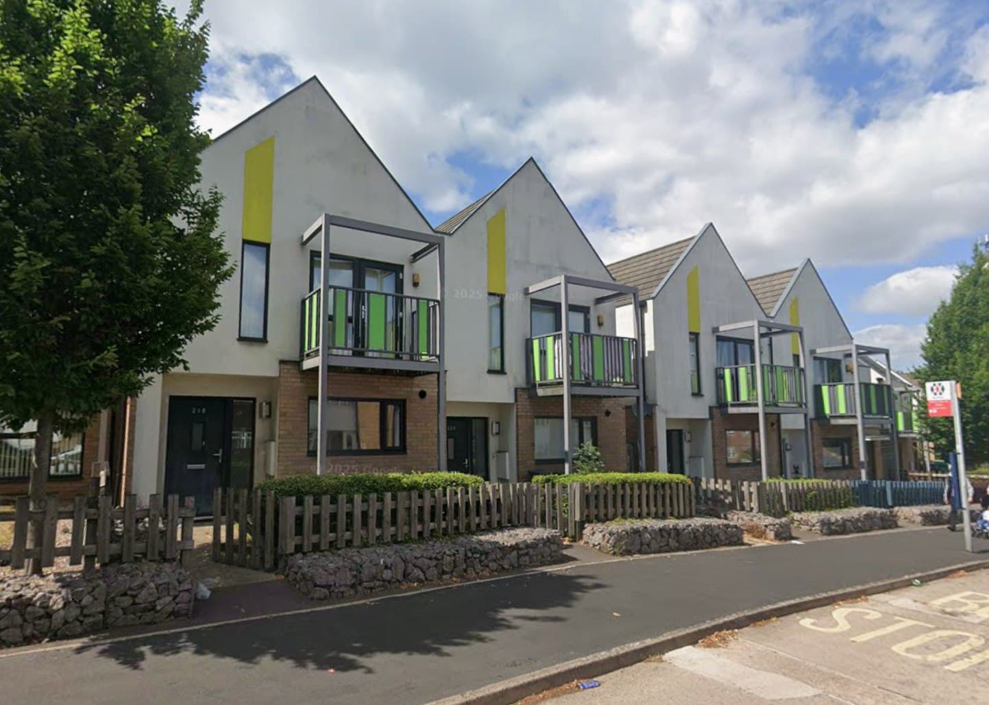 Beaconview Road, West Bromwich: terrace of modern render-and-brick townhouses with mono-pitched roofs, green glass balconies and yellow accent panels behind timber fencing, Accord Housing affordable scheme