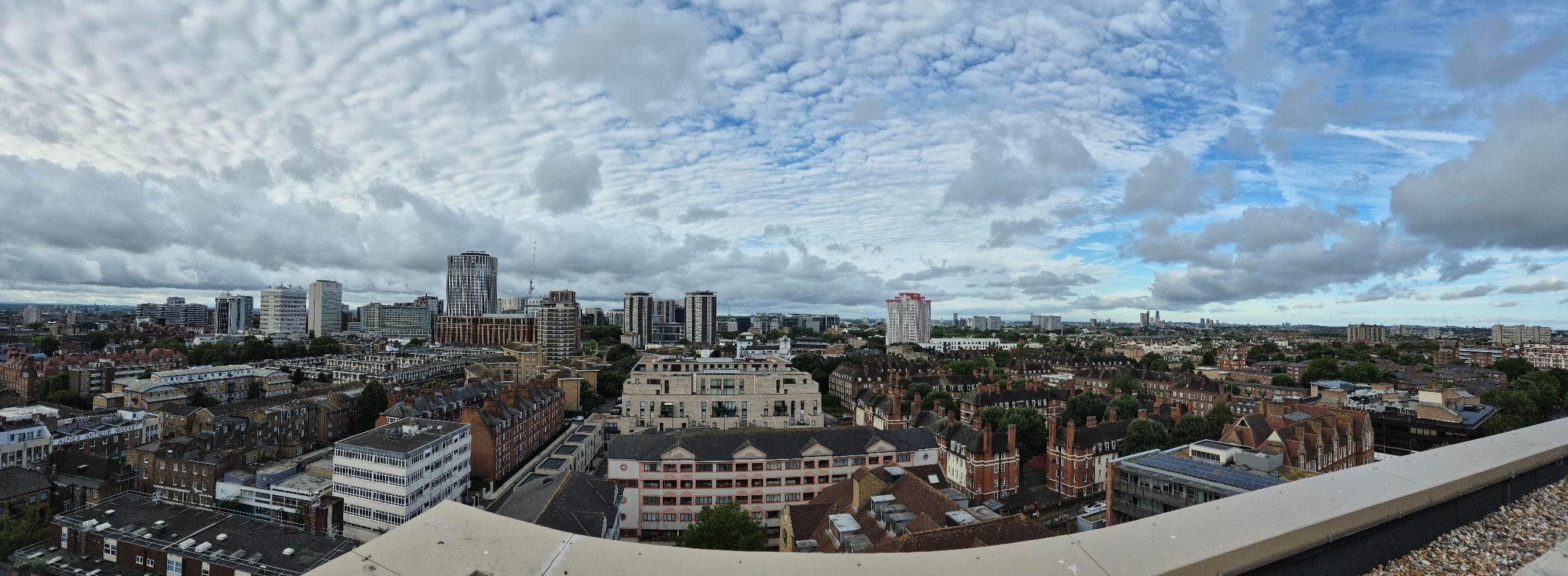 Daventry House (Lisson Arches), Westminster: street view of the cream-brick block from across Lisson Grove, with parked cars, a green Edwardian pub on the corner and the upper darker-brick block of Daventry House rising above