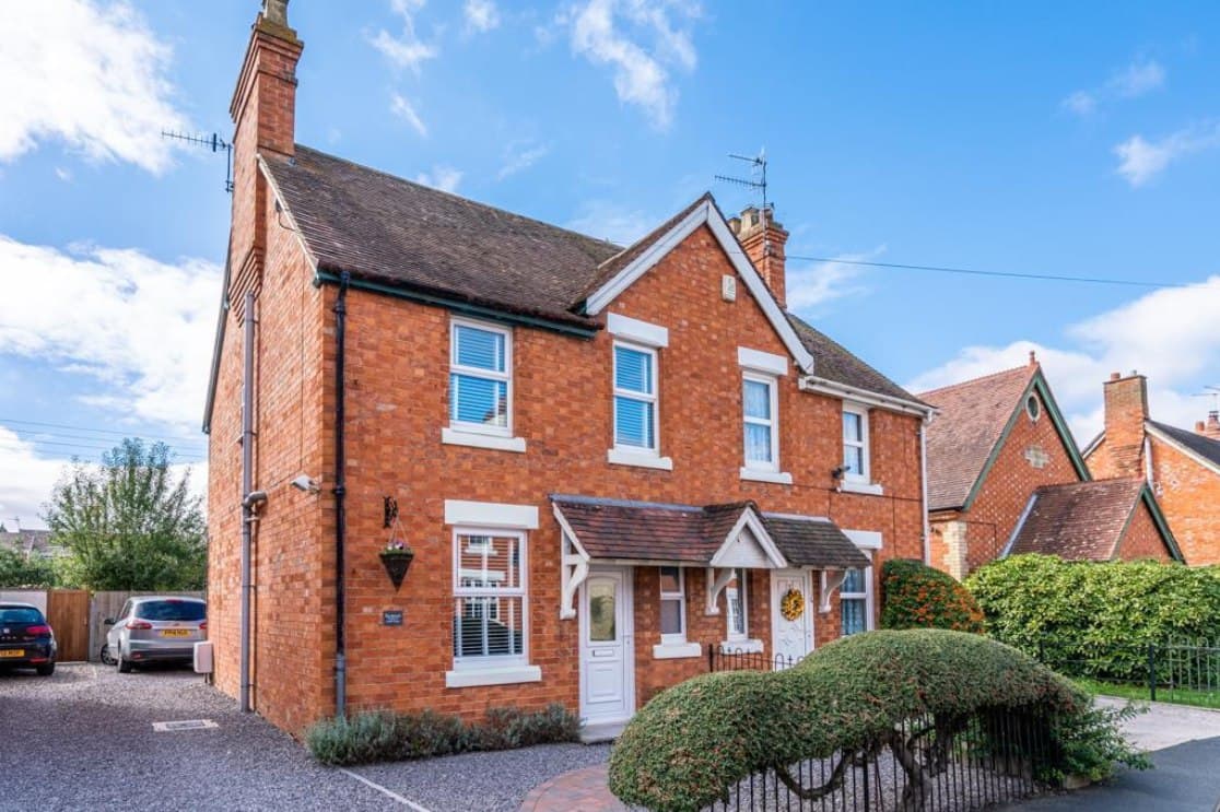 Shinehill Lane, South Littleton: red-brick semi-detached homes with rendered gable detailing, bay windows and hedged front gardens in the sun, Platform Housing Group scheme