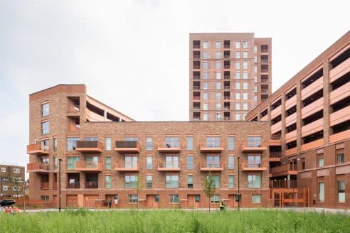 Walter Tull House, Welbourne (Tottenham Hale): completed brick perimeter block with stepped massing, in front of the taller red-brick tower of the same scheme, Argent Related delivery