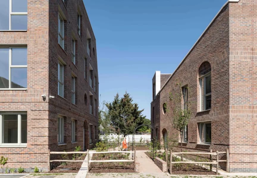 Becontree Avenue, Dagenham: landscaped courtyard between two brick blocks with raised planters and oculus windows