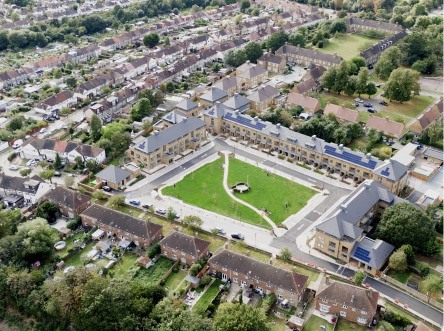 Haig Homes, Morden: aerial view of the completed development, terraces and apartment blocks arranged around a large central green within the surrounding suburban streets, Haig Housing scheme
