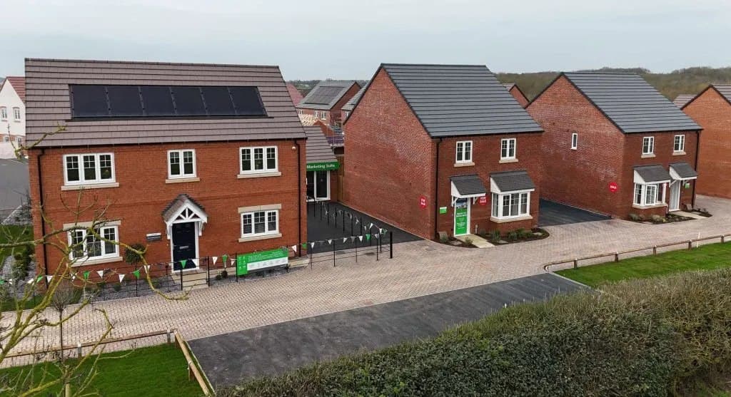 Leicester New Build, Leicester: elevated view across the development, red-brick family homes with roof-mounted solar panels, gardens and driveways along the street, Partner Construction / Balfour Beatty scheme