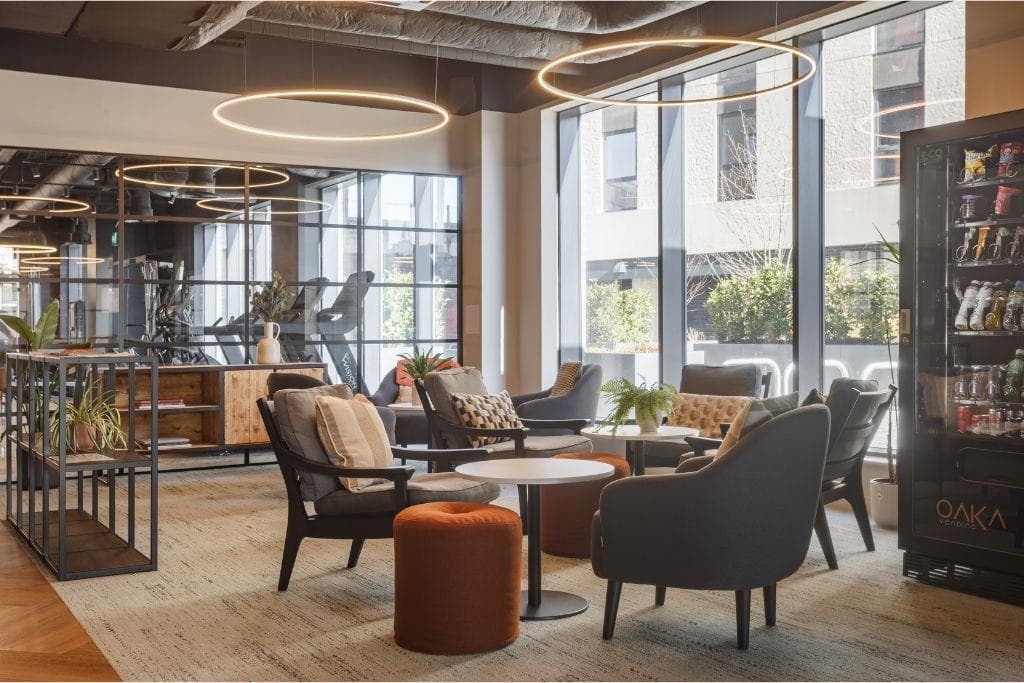 Saxton Heights, Leeds: residents' communal lounge with soft seating, ring pendant lighting and a gym studio beyond floor-to-ceiling windows, affordable scheme for Wakefield District Housing