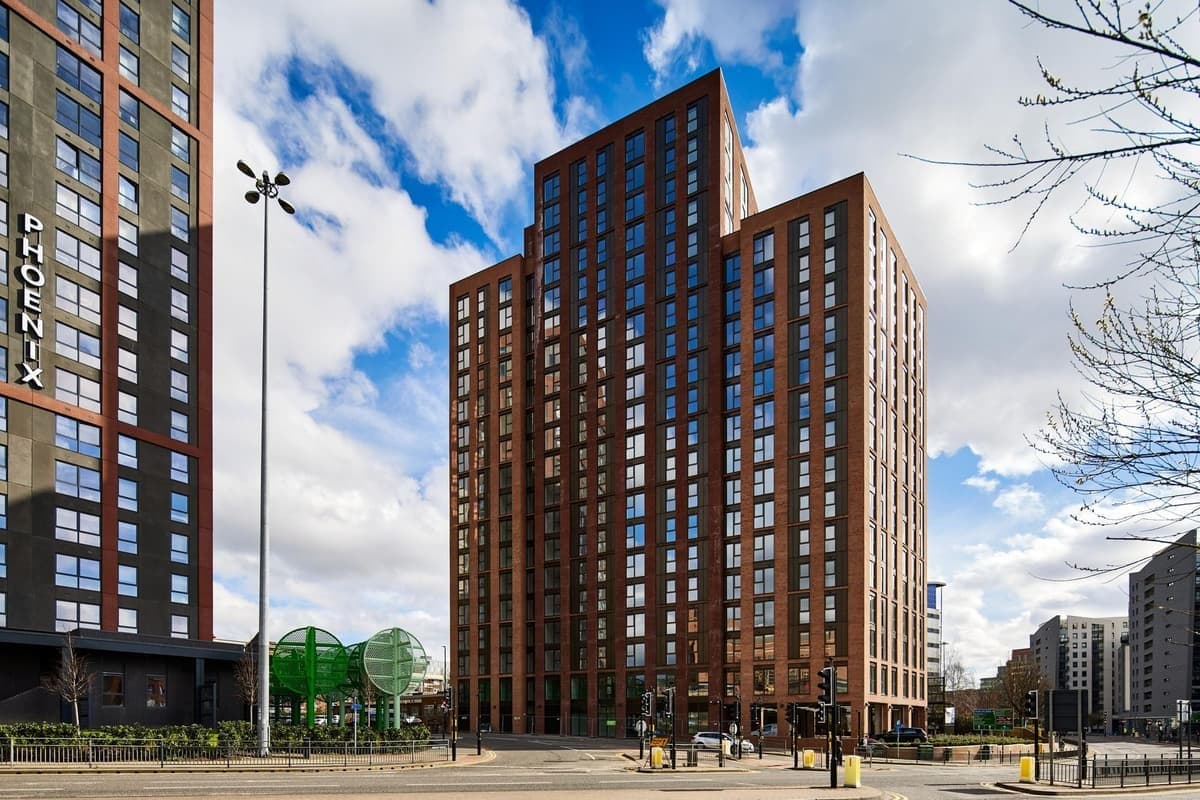 Saxton Heights, Leeds: street-level view of the completed red-brick apartment towers stepping up to 20 storeys against a blue sky, affordable scheme for Wakefield District Housing
